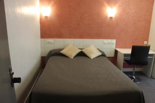 a bedroom with a bed with two pillows on it at Hotel Au Chapon Fin in Poitiers