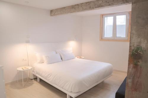a white bed in a room with a window at NUEVO Katu Kale Apartamentuak CENTRO HISTORICO in Getaria