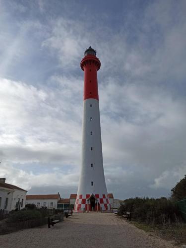 a red and white lighthouse in front of a building at Mobil home 2 chambres Bonne Anse in Les Mathes