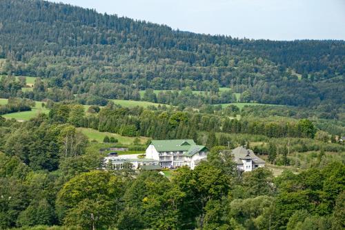 a house in the middle of a valley with trees at Holimo Hotel in Stronie Śląskie