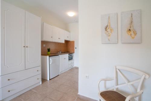 a kitchen with white cabinets and a chair in it at Almira Hotel in Troulos
