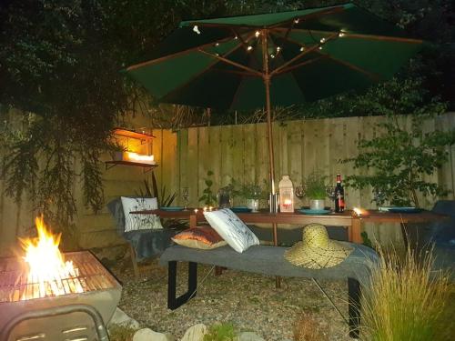 a table with an umbrella and a bench with a fire at Spire View Townhouse in Ballycastle