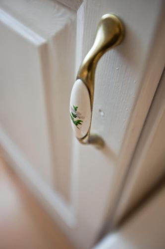 a gold door knob on a white door at Tornácos Hotel - Hegykő in Hegykő