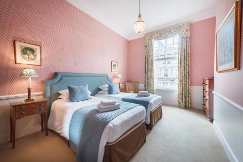 a bedroom with two beds with pink walls and a window at No1 The Mansions By Mansley in London