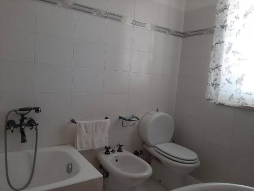 a white bathroom with a toilet and a sink at Colle Alto Pachino - Marzamemi in Pachino