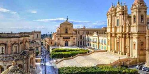a large building with a courtyard in front of it at Colle Alto Pachino - Marzamemi in Pachino