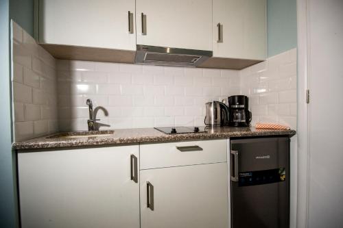 una pequeña cocina con armarios blancos y nevera negra en Diamanti Studios, en Skala Kallonis