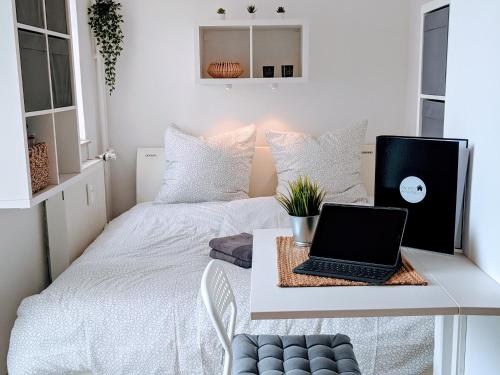 a room with two beds with a laptop on a desk at Tiny Apartment - Innenstadt l Smart TV l Küche in Kaiserslautern
