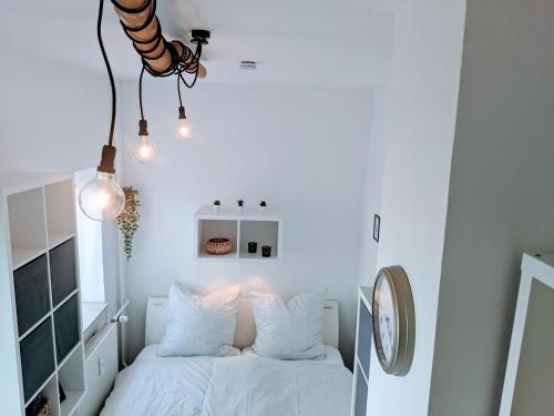 a bedroom with a bed with white sheets and lights at LENASTAY l Tiny Apartment in Top Location in Kaiserslautern