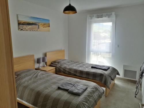 deux lits dans une chambre blanche avec une fenêtre dans l'établissement Appt T3 neuf, draps et serviettes fournis, à Argelès-sur-Mer