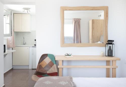 a bedroom with a mirror and a table with a chair at Central Suites Mykonos in Mýkonos City