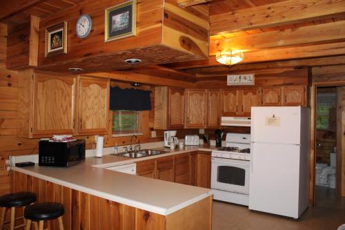 a kitchen with wooden cabinets and a white refrigerator at Country Road Cabins in Hico