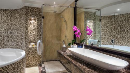 a bathroom with a tub and a large sink at Bahi Ajman Palace Hotel in Ajman 