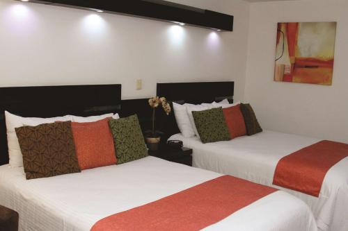 two beds in a hotel room with white and orange at Hotel Poza Rica Centro in Poza Rica de Hidalgo