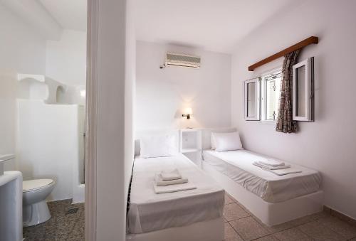 a white room with two beds and a toilet at Kanala Studios in Kithnos
