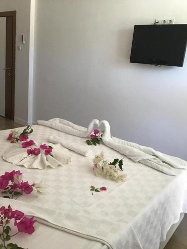 a white bed with flowers on top of it at Altunakar 1 Hotel in Didim