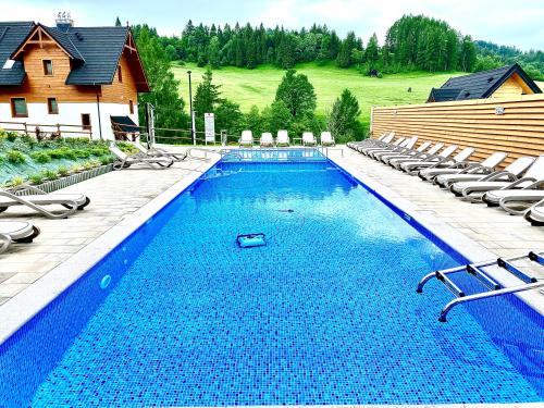 a large swimming pool with chairs and a house at Flisak in Jaworki