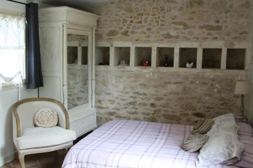 a bedroom with a bed and a chair at Le Clos du Vallon des Courances in Saint-Coutant-le-Grand