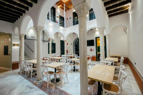 Hotel Cetina Sevilla في إشبيلية: غرفة طعام مع طاولات وكراسي في مبنى