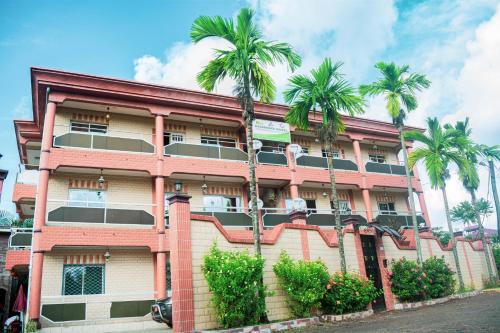 a building with palm trees in front of it at Résidence Hotelière Borel Denver in Douala