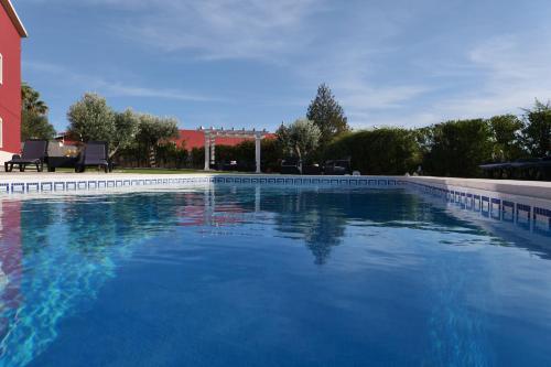 a large swimming pool with blue water in a yard at Casal da Rita Natura in Santarém
