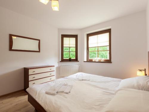 a white bedroom with a bed and two windows at VacationClub - Nadrzeczna 2B Apartament 4 in Karpacz