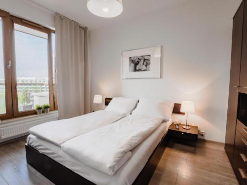 Schlafzimmer mit einem Bett mit weißer Bettwäsche und einem Fenster in der Unterkunft VacationClub - Olympic Park Apartament A605 in Kołobrzeg