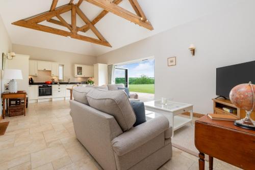 a living room with a couch and a tv at Barrow Hill Barns in Petersfield
