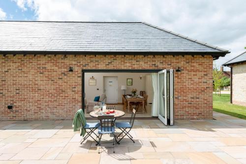 an extension to a brick house with a table and chairs at Barrow Hill Barns in Petersfield