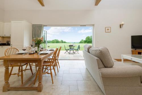 a living room with a table and chairs and a television at Barrow Hill Barns in Petersfield