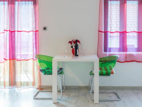 a white table and two green chairs in a room at Apartments Windrose in Kotor