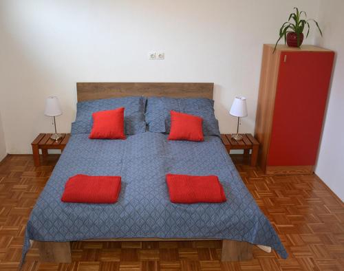 a bedroom with a blue bed with red pillows at Apartma Vidmar in Šenčur