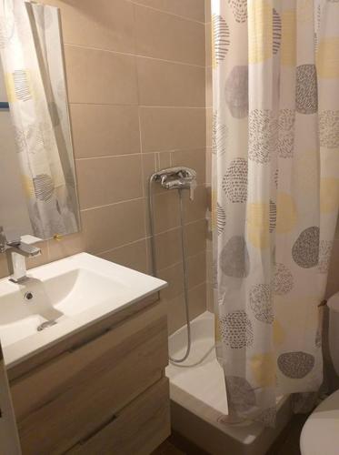 une salle de bain avec un lavabo et un rideau de douche dans l'établissement maison de la plage, au Grau-du-Roi