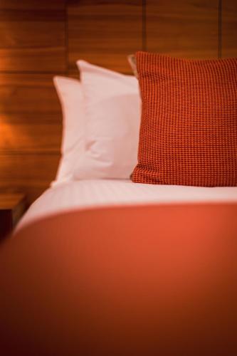 a bed with a red pillow and white sheets at The Knight Residence by Mansley in Edinburgh