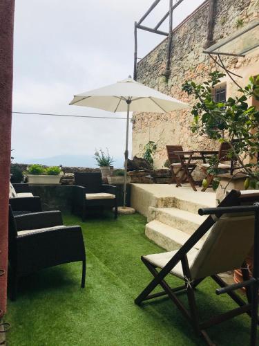 a patio with chairs and an umbrella and grass at Crosa tra le Nuvole in Borgio Verezzi