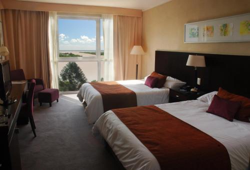 a hotel room with two beds and a large window at Howard Johnson Plaza Resort & Casino Mayorazgo in Paraná