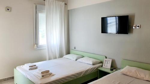two beds in a room with a tv on the wall at Seaside Luxury Suites by Sarigianni in Paralia Katerinis