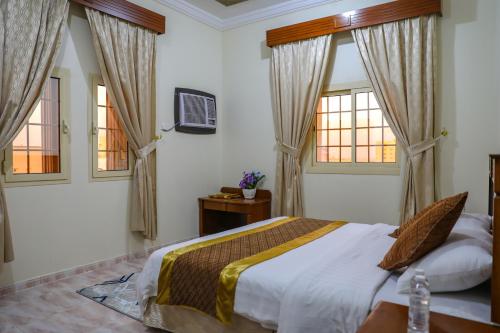 a bedroom with a bed and two windows at الارجوان الراقية in Yanbu
