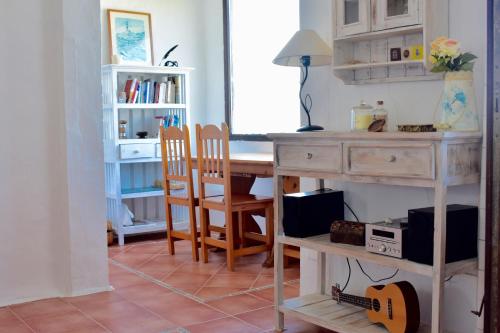 een kamer met een bureau en een tafel met een gitaar bij Apartamento en el mar con terraza in Fornells