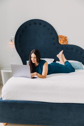 a woman laying on a bed with a laptop at 5 Hermoupolis Concept Sites in Ermoupoli