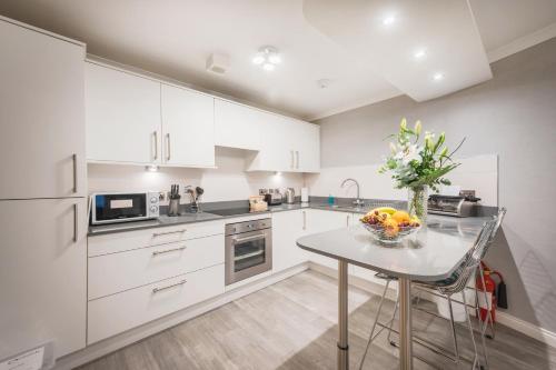 a kitchen with white cabinets and a table with a bowl of fruit at The Knight Residence by Mansley in Edinburgh