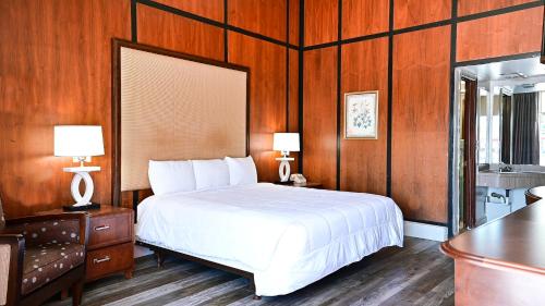 a bedroom with a white bed and wooden walls at OAKS MOTEL GREENSBORO NC in Greensboro