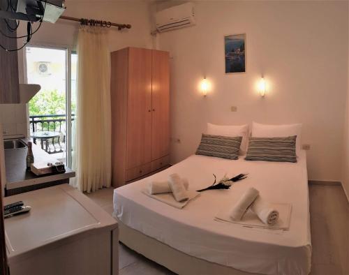 a bedroom with a white bed with two shoes on it at Sea La Vie - Studios Maria in Limenaria