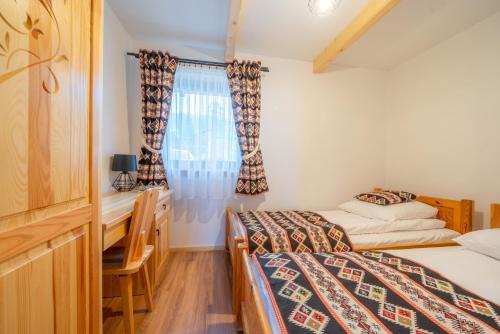 1 Schlafzimmer mit 2 Betten, einem Schreibtisch und Vorhängen in der Unterkunft Villa Kierpcóweczka in Kościelisko