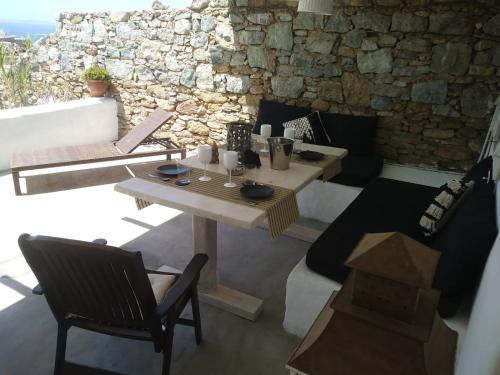 einen Tisch und Stühle in einem Zimmer mit einer Steinmauer in der Unterkunft PEQUEÑA CASA CERCA DE MIKONOS CIUDAD in Mykonos Stadt