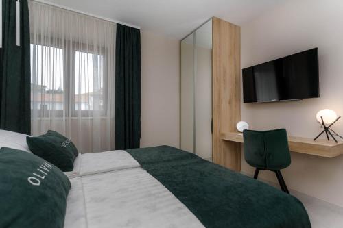 a bedroom with a large bed with a flat screen tv at Apartments Olivia & Navy, Šilo in Šilo