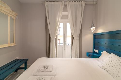 Un dormitorio con una cama azul y una ventana en Casa Patio del Panadero, en Cádiz