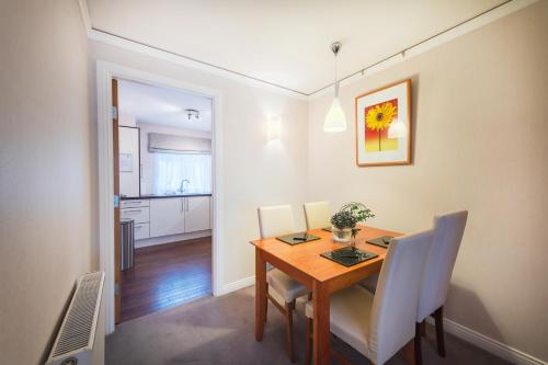a dining room with a wooden table and white chairs at The Knight Residence by Mansley in Edinburgh