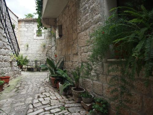 a stone alley with potted plants on the side of a building at Rooms & Studio Stipcic in Trogir