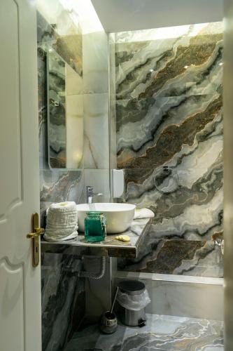 a bathroom with a sink and a painting on the wall at Family Inn Apartments&suites in Neos Marmaras